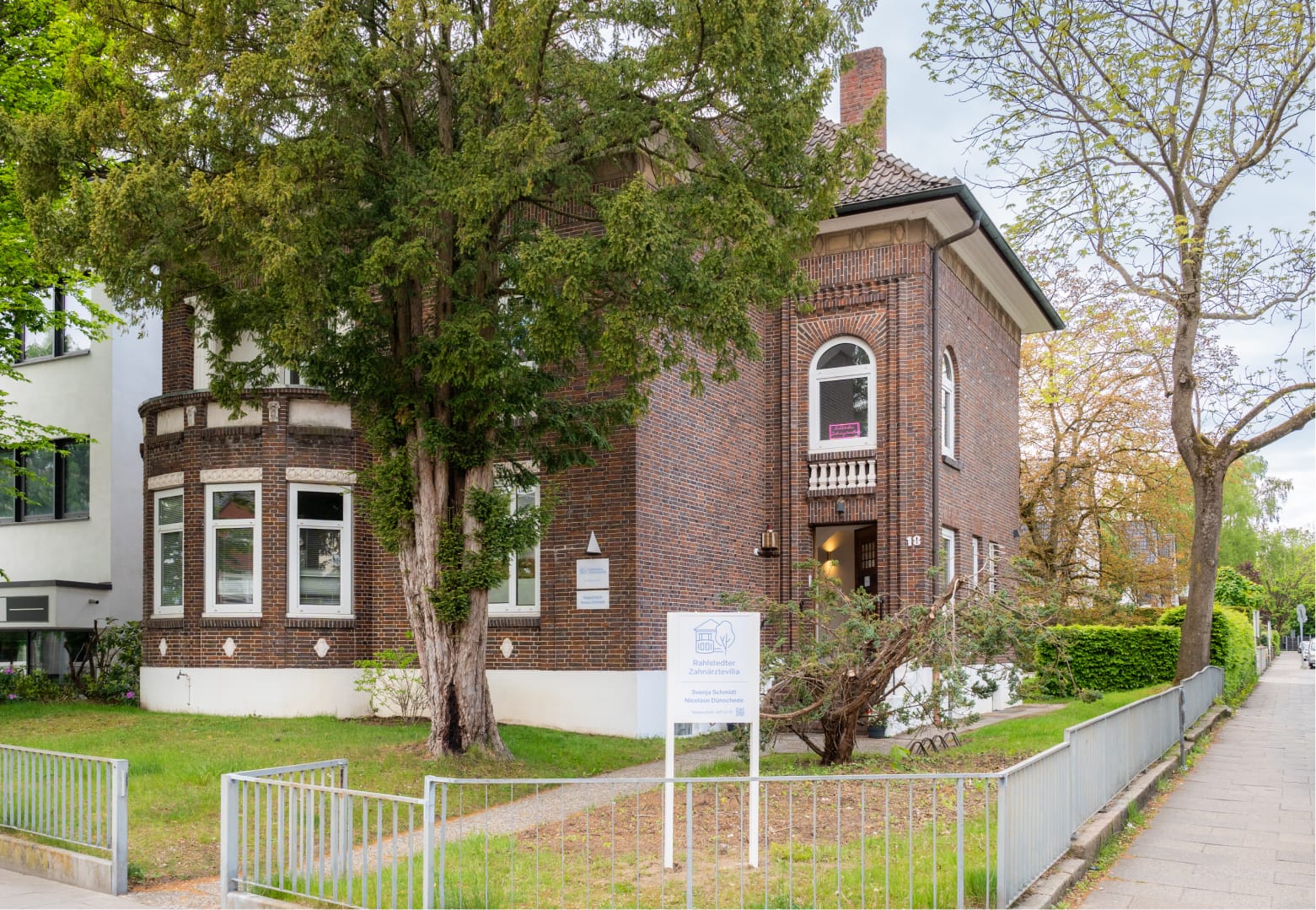 Gesamtansicht der Rahlstedter Zahnärztevilla mit Garten und Praxisschild